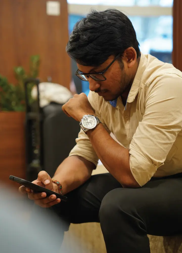 edwin roy a digital marketer specialised in SEO is Scrolling through his phone sitting at SLBS Marklance in Kochi.